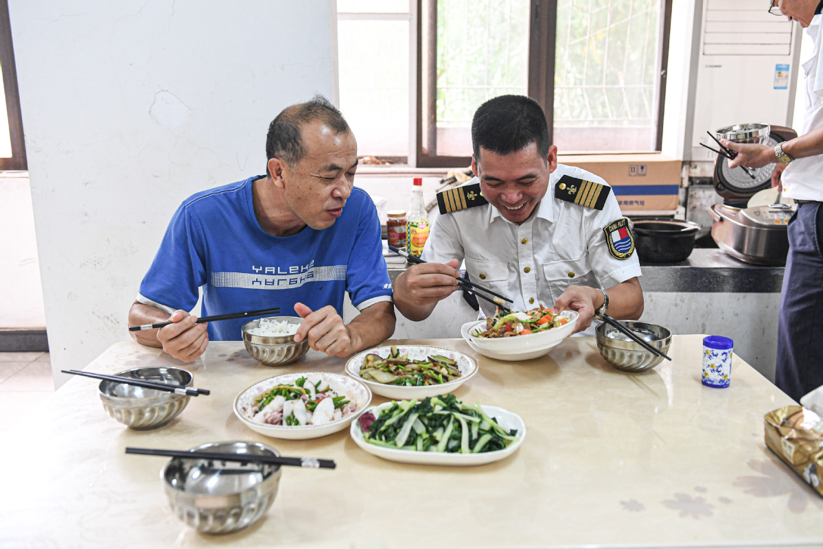 Lin Hongpin (right) returns to the station in Yangpu and chats with Lin Daoming during lunch. [Photo by Pu Xiaoxu/Xinhua]